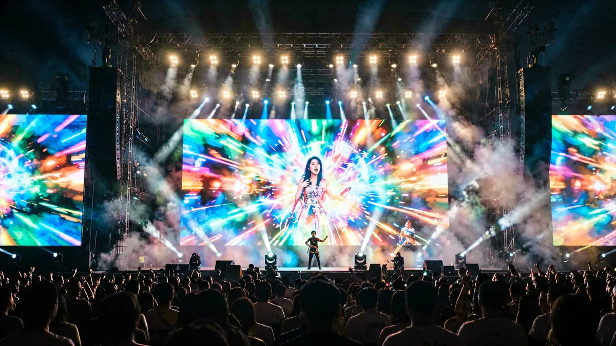Giant LED stage screen behind a live concert with stage lighting and audience silhouettes, driven by a Huidu control system
