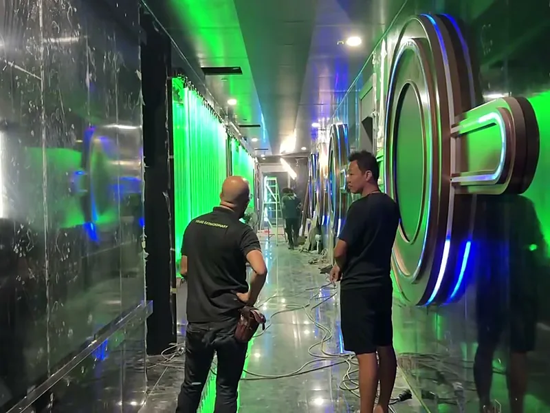 LED screens along a bar corridor with green ambient light