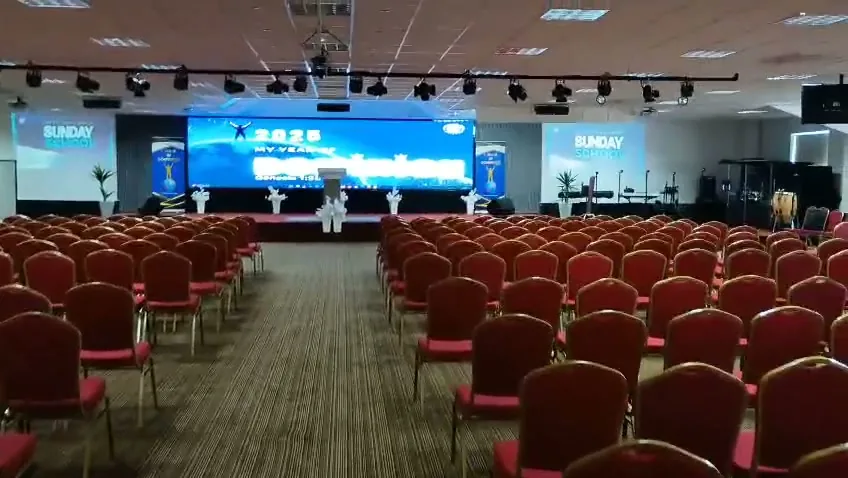 Video still: church hall with red chairs and LED screen at RCCG Church Swindon UK