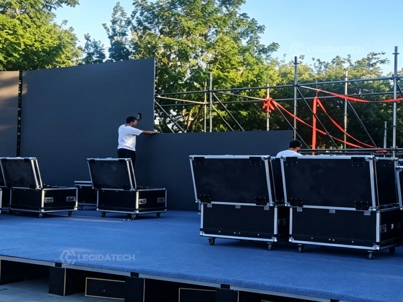 Crew placing AF1000 500x1000mm rental LED display cabinets to build a large stage backdrop against the clock