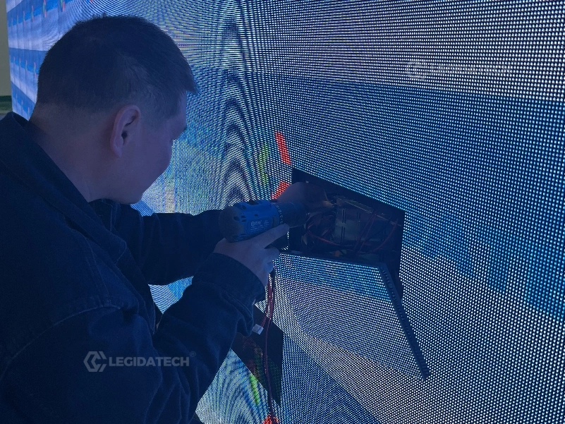 Engineer swapping an LED module from the front of an AF1000 500x1000mm rental LED display cabinet against a wall
