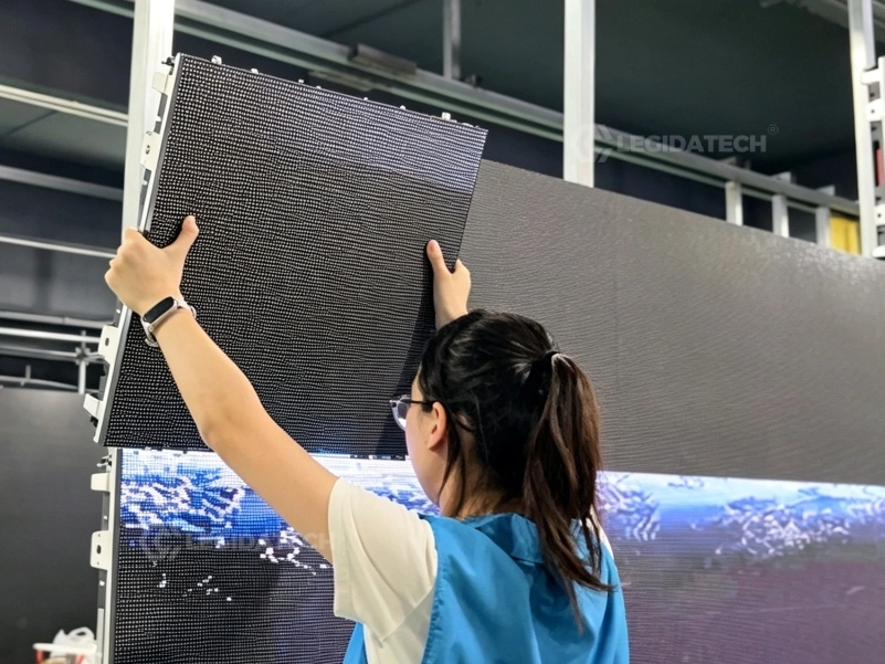 Technician lifting and locking a single AF500 500x500mm rental LED display cabinet by hand during a fast load-in