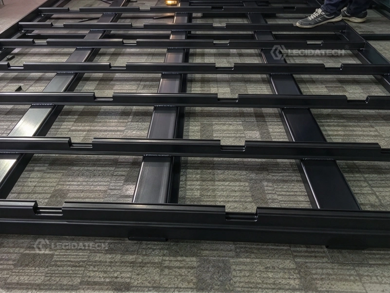 Installers sliding 500x1000mm LED floor cabinets onto guide rails during assembly of a large floor screen