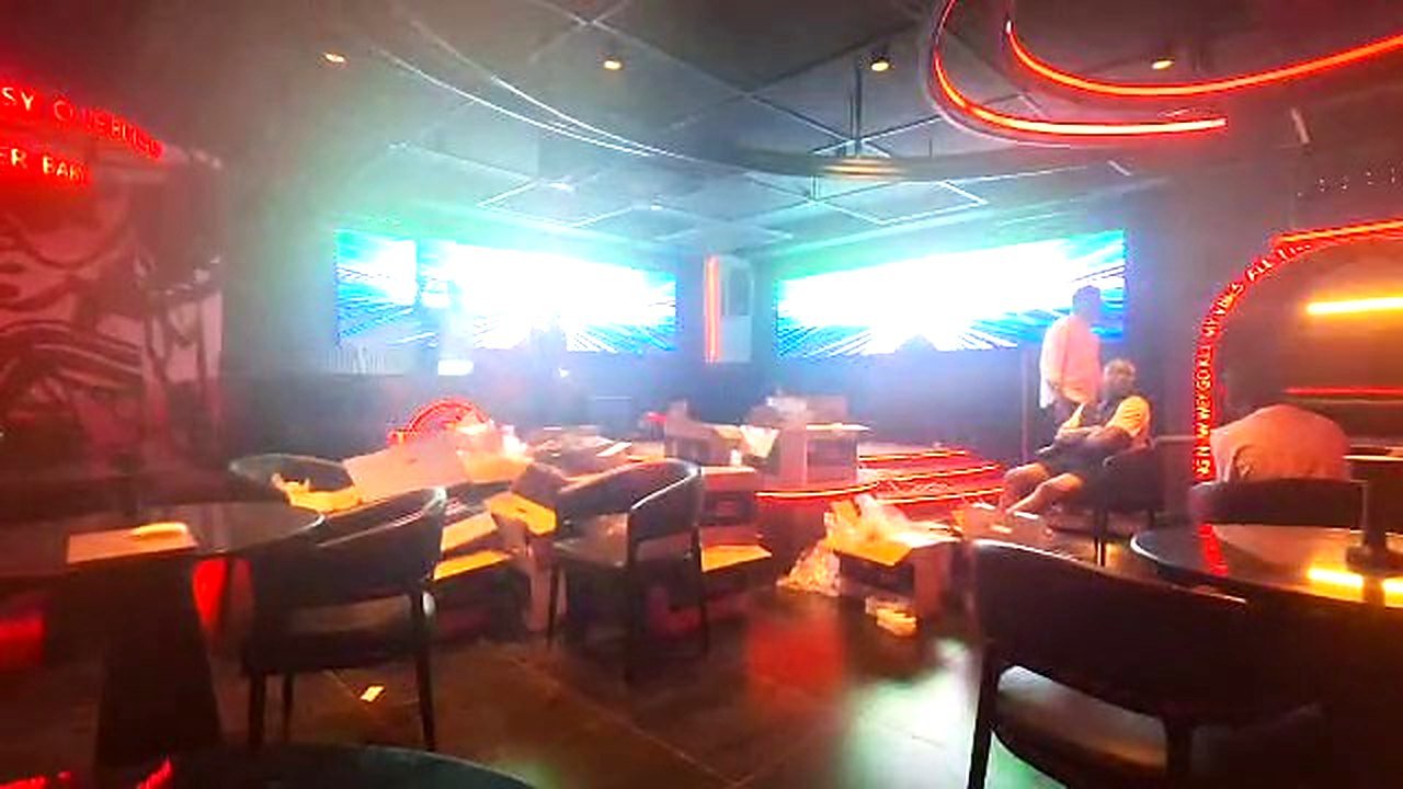 Video still: wide view of the nightclub interior at Toppest Lekki with the two P2.5 LED screens, red-lit stage steps and neon signage