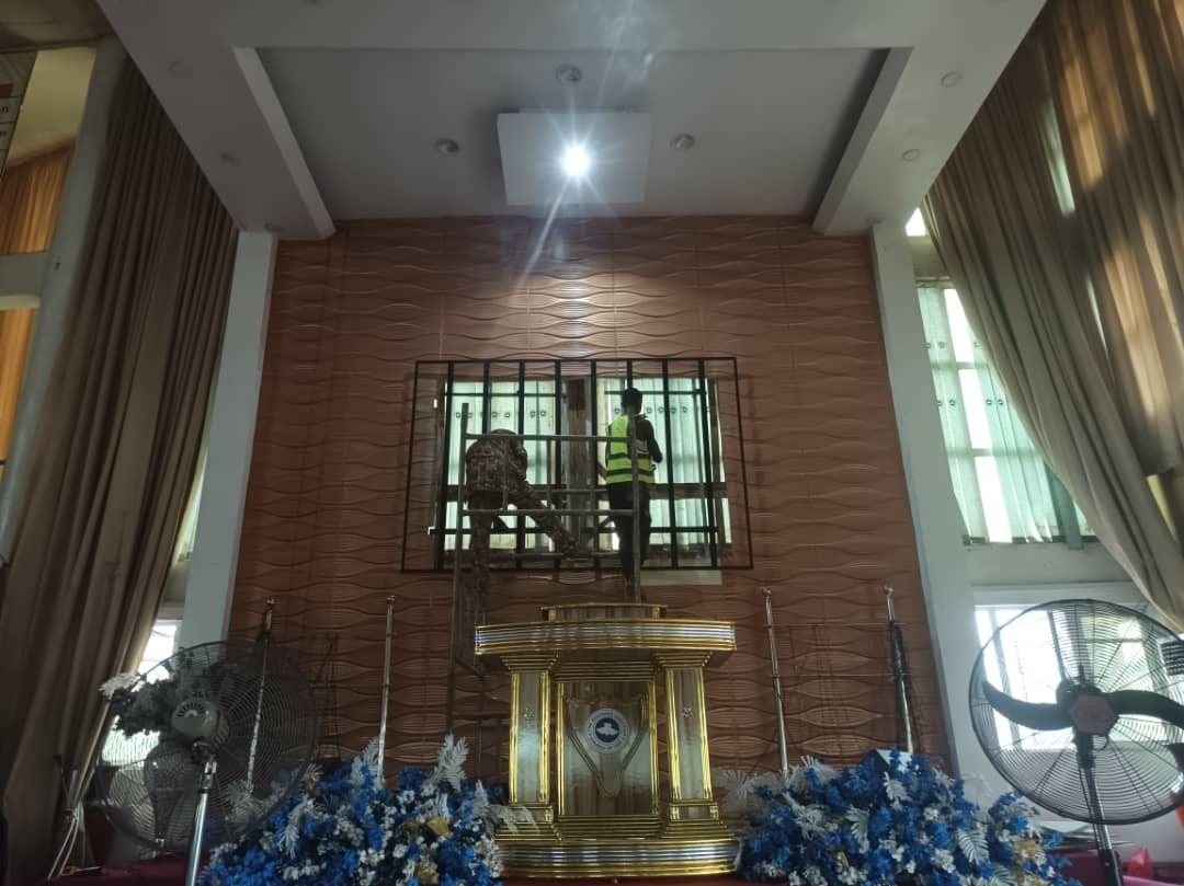 Photo from the project site: workers at the screen position above the altar during the Ehonor P2.5 church LED screen installation at RCCG Jesus Mega Sanctuary, Akowonjo, Lagos