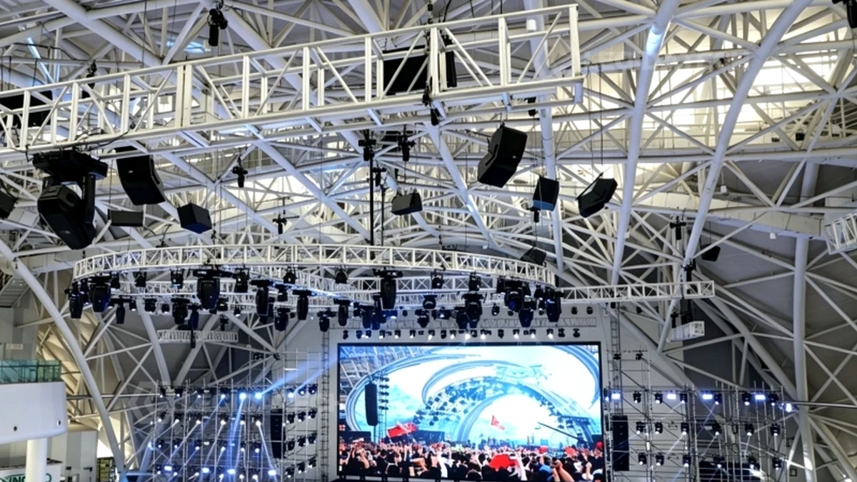 Large LED screen on a truss stage inside a tall exhibition hall